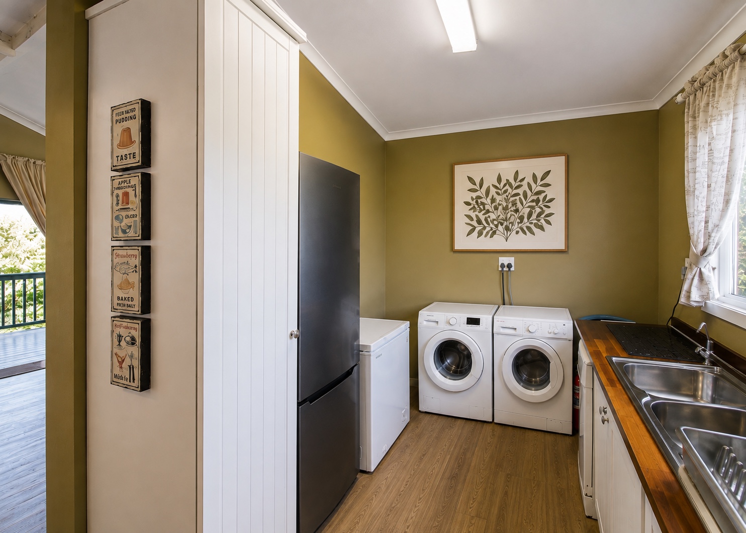 House 1 utility room with fridge-freezer, chest freezer, washing machine, tumble dryer, double sink and fitted storage